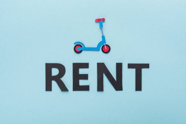 Kağıt kesiği tekme scooter ve mavi arkaplanda siyah kira harflerinin üst görünümü