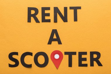 Kağıdın üst görünümü siyah kirayı kesti. Turuncu arka planda bir scooter harfi ve kırmızı konum işareti var.