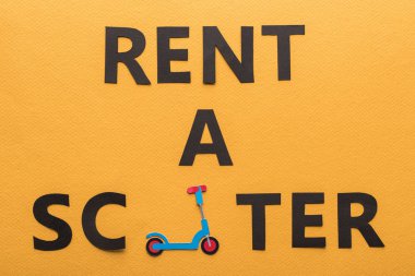 Kağıdın üst görünümü turuncu arka planda bir scooter kiraladı