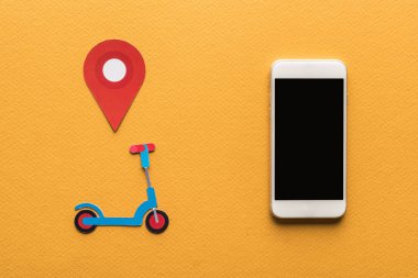 Kağıt kesikli scooter 'ın üst görünümü, akıllı telefonun yanında konum işareti turuncu arka planda boş ekran
