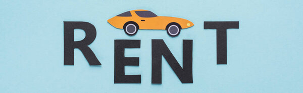 top view of paper cut sports car and black rent lettering on blue background, panoramic shot