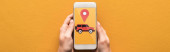 cropped view of woman holding smartphone with rent car app on orange background, panoramic shot