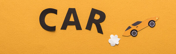 top view of paper cut sports car with exhaust gas and black car lettering on orange background, panoramic shot