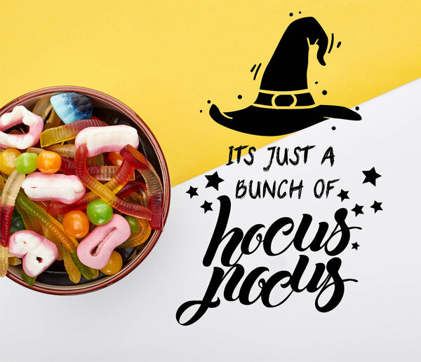top view of colorful gummy sweets in bowl on yellow and white background with it is just a bunch of hocus pocus illustration