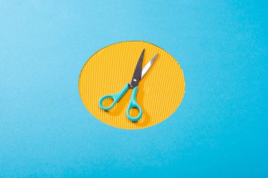 high angle view of metal scissors on yellow circle  clipart