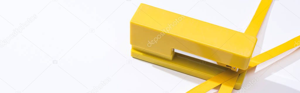 panoramic shot of stapler and paper strips on white background 