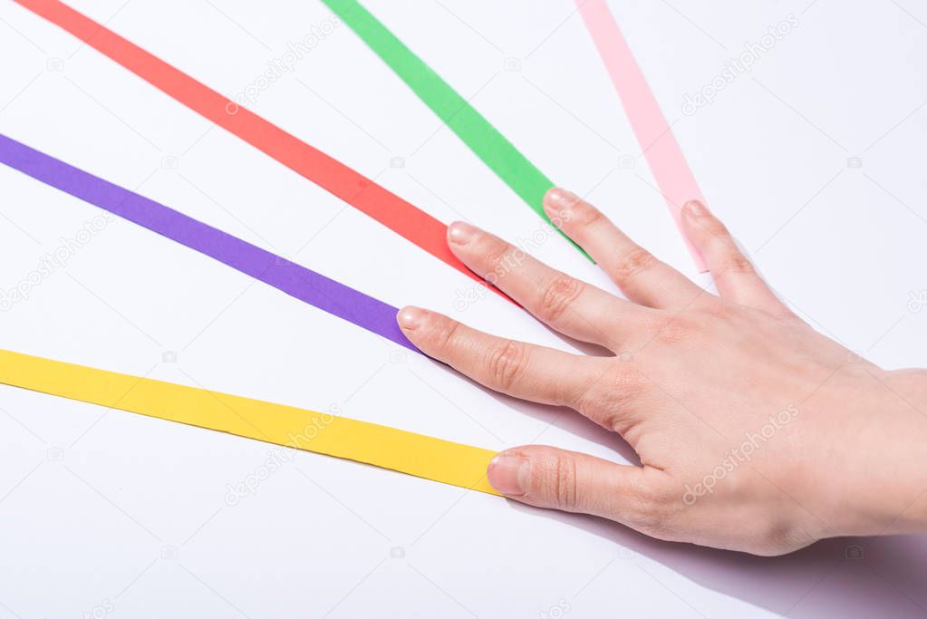 cropped view of woman touching colorful paper strips on white background