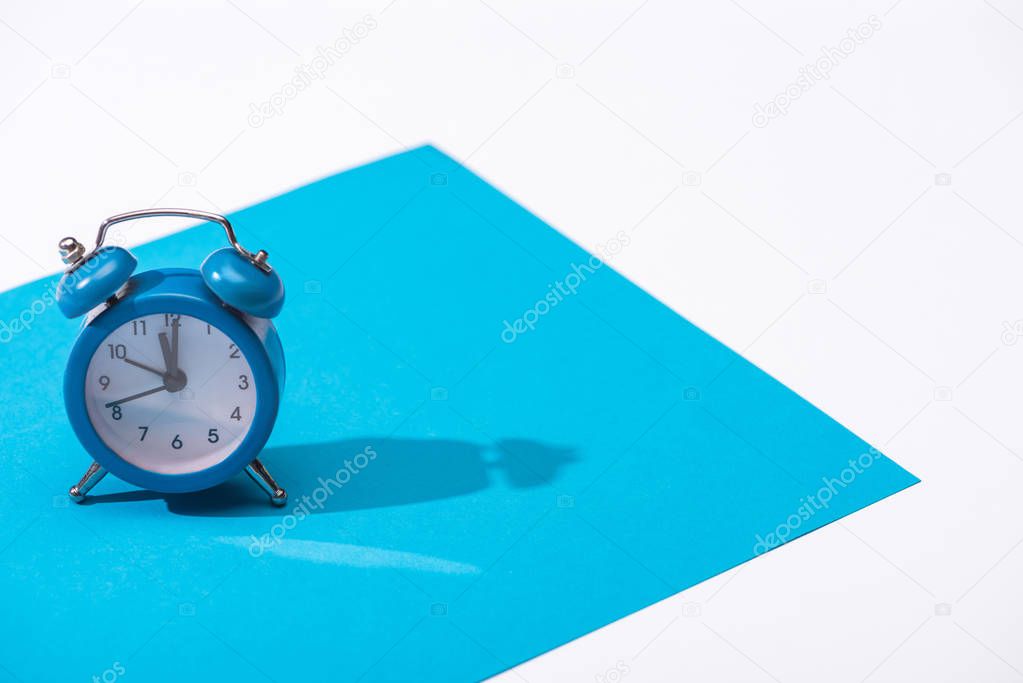 high angle view of alarm clock and blue paper isolated on white 
