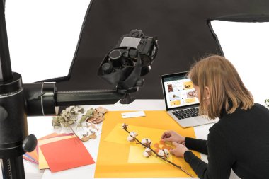 Fotoğraf makinesi ve laptop ile fotoğraf çekimi için pamuk çiçeği ve aksesuarlarla kompozisyon hazırlayan fotoğrafçı