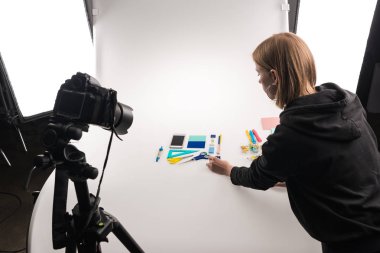 Profesyonel fotoğrafçı, beyaz üzerine ticari fotoğraf çekimi için ofis malzemeleriyle yatıyordu.