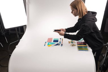 commercial photographer making photos of office supplies on smartphone clipart