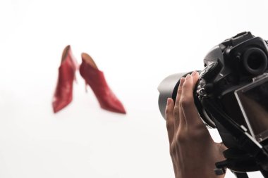 cropped view of female photographer making commercial photo shoot of female red heel shoes on white clipart
