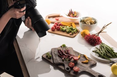 Ticari fotoğrafçılık için yemek hazırlayan ve dijital kamerada fotoğraf çeken kadın fotoğrafçı görüntüsü. 