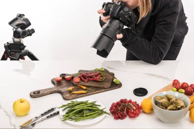 Kadın fotoğrafçı ticari fotoğrafçılık için yemek kompozisyonu hazırlıyor ve dijital kamerada fotoğraf çekiyor. 