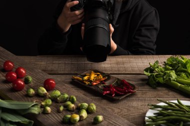Ticari fotoğrafçılık için besin oluşturan kadın fotoğrafçı görüntüsü ve ahşap masadaki dijital kamerada fotoğraf çekimi.