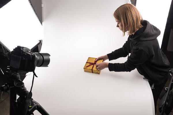 beautiful photographer taking photos of christmas gift on digital camera on white in photo studio