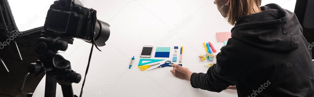cropped view of photographer making flat lay with office supplies for commercial photo shooting on white, panoramic shot