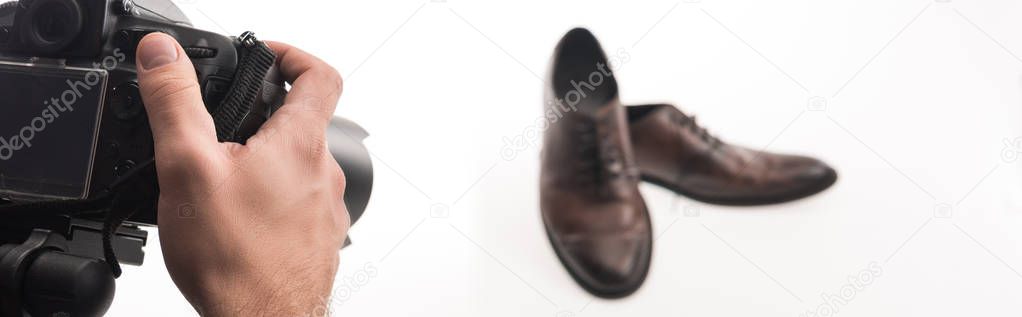 partial cropped view of male photographer making commercial photo shoot of male shoes on white, panoramic shot