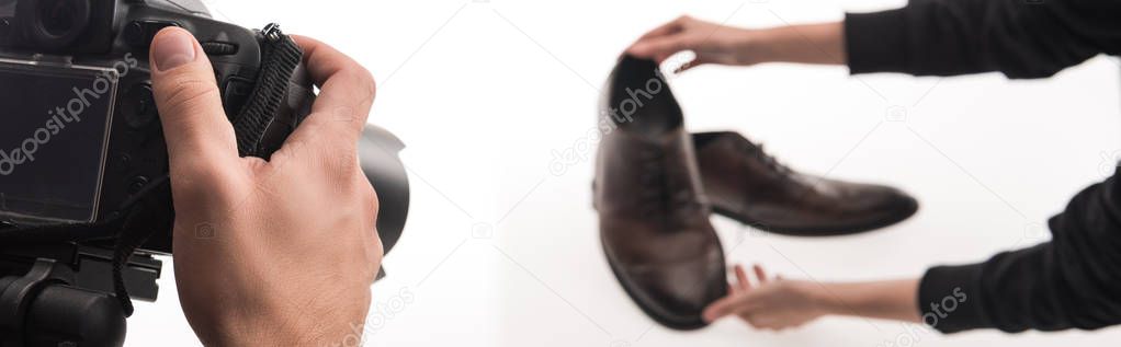 cropped view of commercial photographers making photo shoot of male shoes on white, panoramic shot