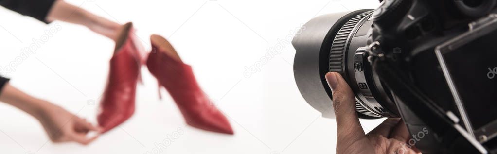 cropped view of photographers making commercial photo shoot of female red heel shoes on white, panoramic shot