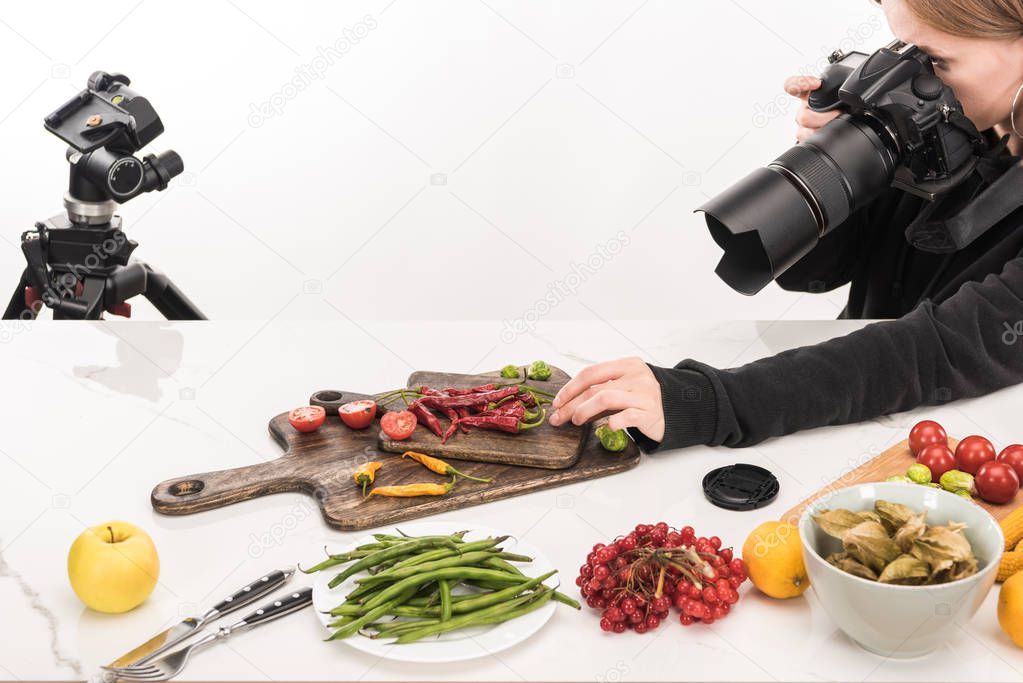 female photographer making food composition for commercial photography and taking photo on digital camera 