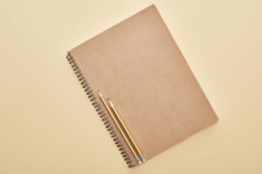 top view of  paper blank notebook with pencils on beige background clipart