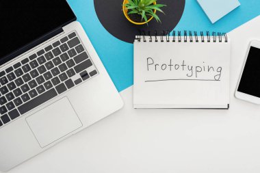 Dizüstü bilgisayarın üst görünümü, akıllı telefon, bitki, soyut geometrik arkaplan üzerinde prototip harfleri olan defter