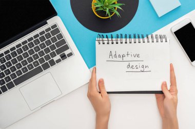 Laptop, akıllı telefon, soyut geometrik arkaplanda bitki gibi uyarlamalı dizayn harfleri olan bir not defteri tutan kadın görüntüsü.