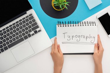 Dizüstü bilgisayar, akıllı telefon, soyut geometrik arkaplan üzerine yerleştirilmiş tipografi harfli bir not defteri tutan kadının kırpılmış görüntüsü
