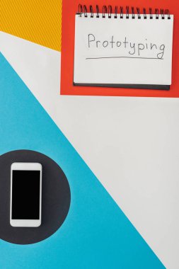 Soyut geometrik arkaplan üzerinde prototip harfleri ve akıllı telefonu olan dizüstü bilgisayarın üst görünümü