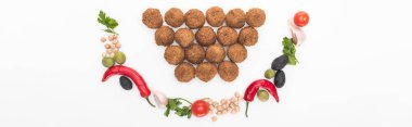 Nohut, sarımsak, kiraz, domates, maydanoz, zeytin, kırmızı biber, yeşil soğan tebessümle sıralanmış falafel toplarının yanında beyaz arka planda panoramik çekim