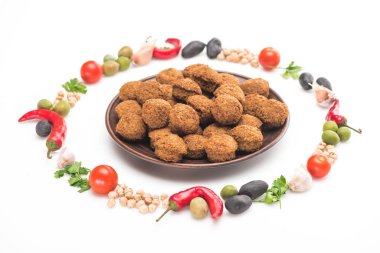 Nohut, sarımsak, kiraz domatesleri, maydanoz, zeytin, biber, yeşil soğan yuvarlak çerçeveli yeşil soğan falafel toplarının etrafında beyaz arka planda.
