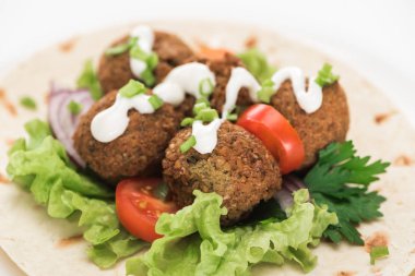 Pide üzerine taze falafel topları, sebzeler ve beyaz arka planda sos.