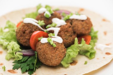 Pide üzerine taze falafel topları, sebzeler ve beyaz arka planda sos.