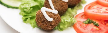 Beyaz arka planda dilimlenmiş sebzelerle soslu falafel manzarasını kapat, panoramik çekim