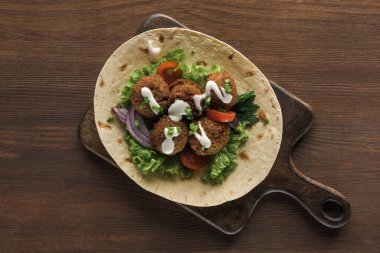 Sebzeli falafel ve ahşap masadaki pide sosu.