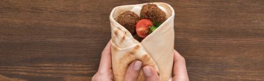 Sebzeli ve soslu falafeli ahşap masada panoramik çekim yapan kadın görüntüsü.