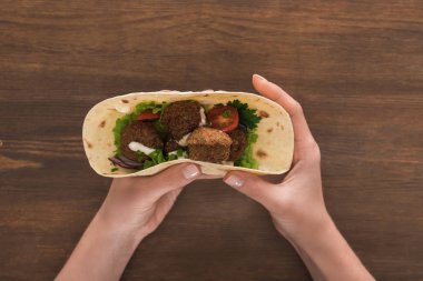 Sebzeli falafel ve ahşap masada pide soslu kadın manzarası.