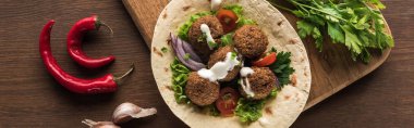 Baharatların yanındaki ahşap masada sebzeli falafelin ve sosun üst görüntüsü, panoramik çekim
