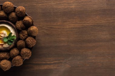 Tahta masada üzerinde humus bulunan falafel toplarının üst görüntüsü.