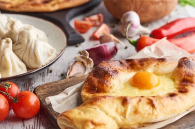 Selective focus of adjarian khachapuri and khinkali on table with vegetables clipart