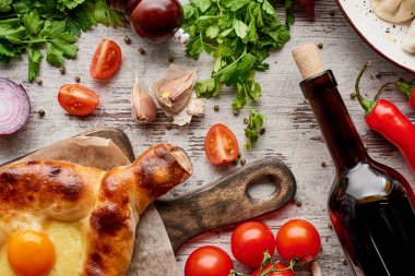 Adjarian Khachapuri, şarap şişesi, ahşap masada kişniş ve kişniş manzarası.