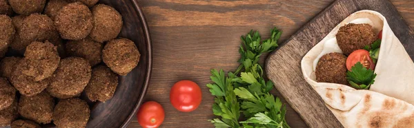 ボールの近くのピタの野菜とソースとファラフェルのトップビュー パセリ 木のテーブルの上のトマト パノラマショット — ストック写真