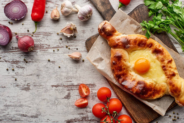 Adjarian khachapuri with vegetables, spices and cilantro on table