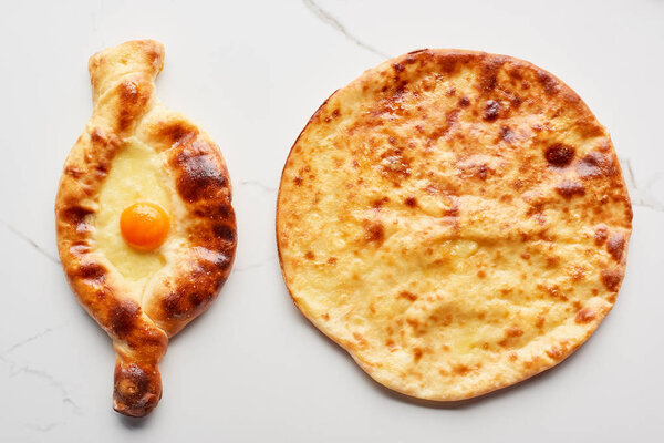 Top view of traditional Georgian adjarian and imereti khachapuri on marble texture