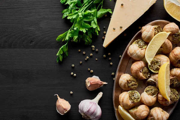 Ovanifrån Läckra Tillagade Escargots Med Citronskivor Svart Träbord Med Ingredienser — Stockfoto