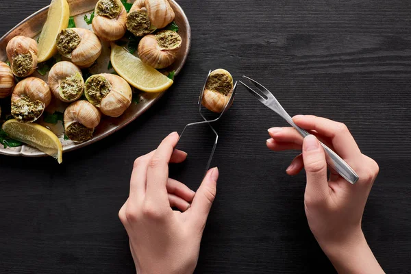 Vista Recortada Mujer Comiendo Deliciosas Escargots Con Limón Mesa Madera — Foto de Stock