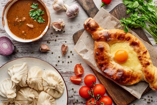 Traditional adjarian khachapuri, soup kharcho and khinkali with vegetables and spices on table — Stock Image Traditional Adjarian Khachapuri Soup Kharcho Khinkali Vegetables Spices Table Stock Picture