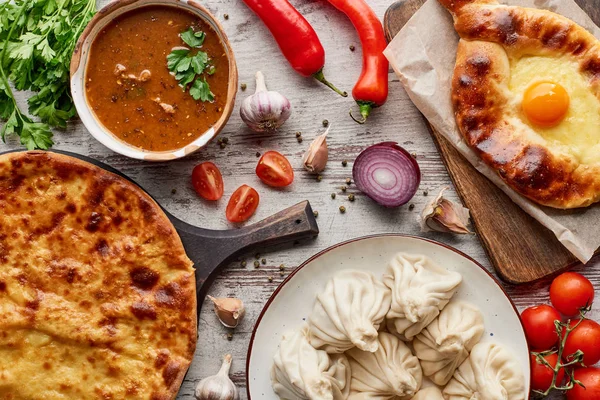 Aadjarian and imereti khachapuri, khinkali and soup kharcho on table with vegetables — Stock Image Aadjarian Imereti Khachapuri Khinkali Soup Kharcho Table Vegetables Stock Image
