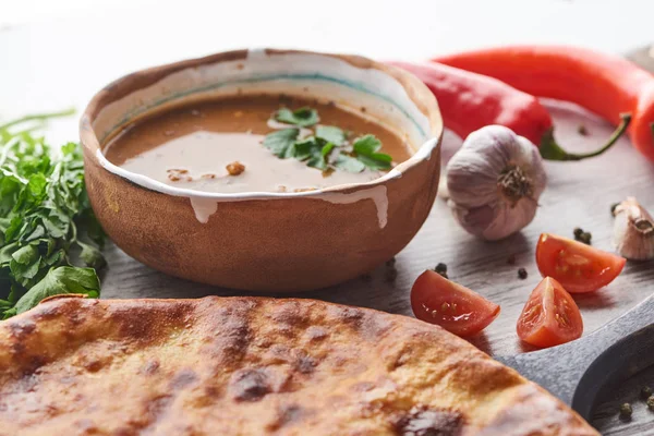 Imereti khachapuri and soup kharcho with cilantro and vegetables on table — Stock Image Imereti Khachapuri Soup Kharcho Cilantro Vegetables Table Stock Picture